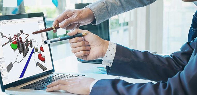 Group of business people working. The team are standing and sitting at a board room table looking at a laptop computer. All dressed in casual business clothing with a window behind them